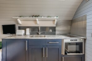 A modern kitchen with a built-in oven, a coffee maker, and a TV mounted on the wall. - 1 Bed in Forfar (oc-t34621) (Forfar)