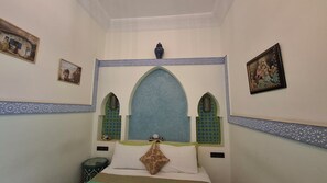 A room with a bed, a nightstand, a decorative vase, and two wall-mounted picture frames. - Riad Med Agorà (Marrakech)