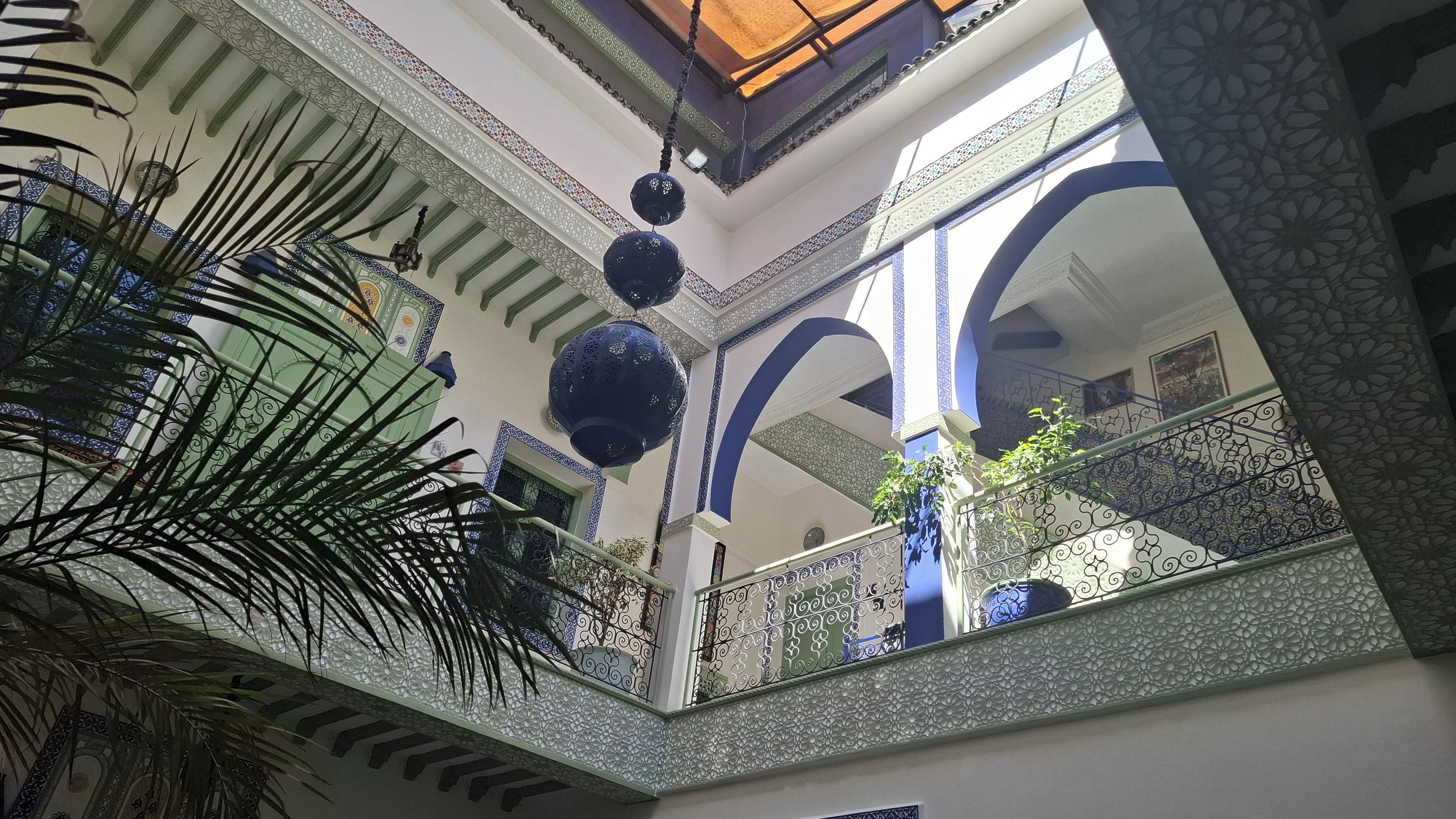 Un interior de varios niveles con barandillas ornamentadas, iluminación decorativa y vistas al exterior.
