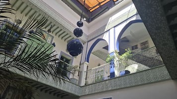 Un interior de varios niveles con barandillas ornamentadas, iluminación decorativa y vistas al exterior.