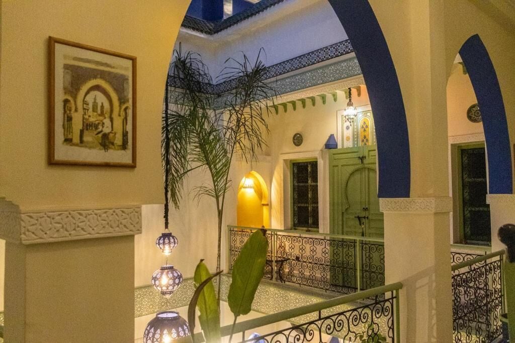 Un patio interior con una escalera, una puerta verde y un cuadro en la pared.