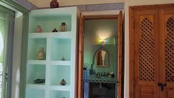 Un pasillo con piso de baldosas, una puerta de madera y una repisa con objetos decorativos.