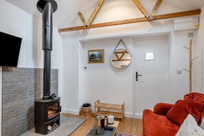 Ein gemütliches Wohnzimmer mit Kamin, Fernseher, Spiegel und einem roten Sofa.