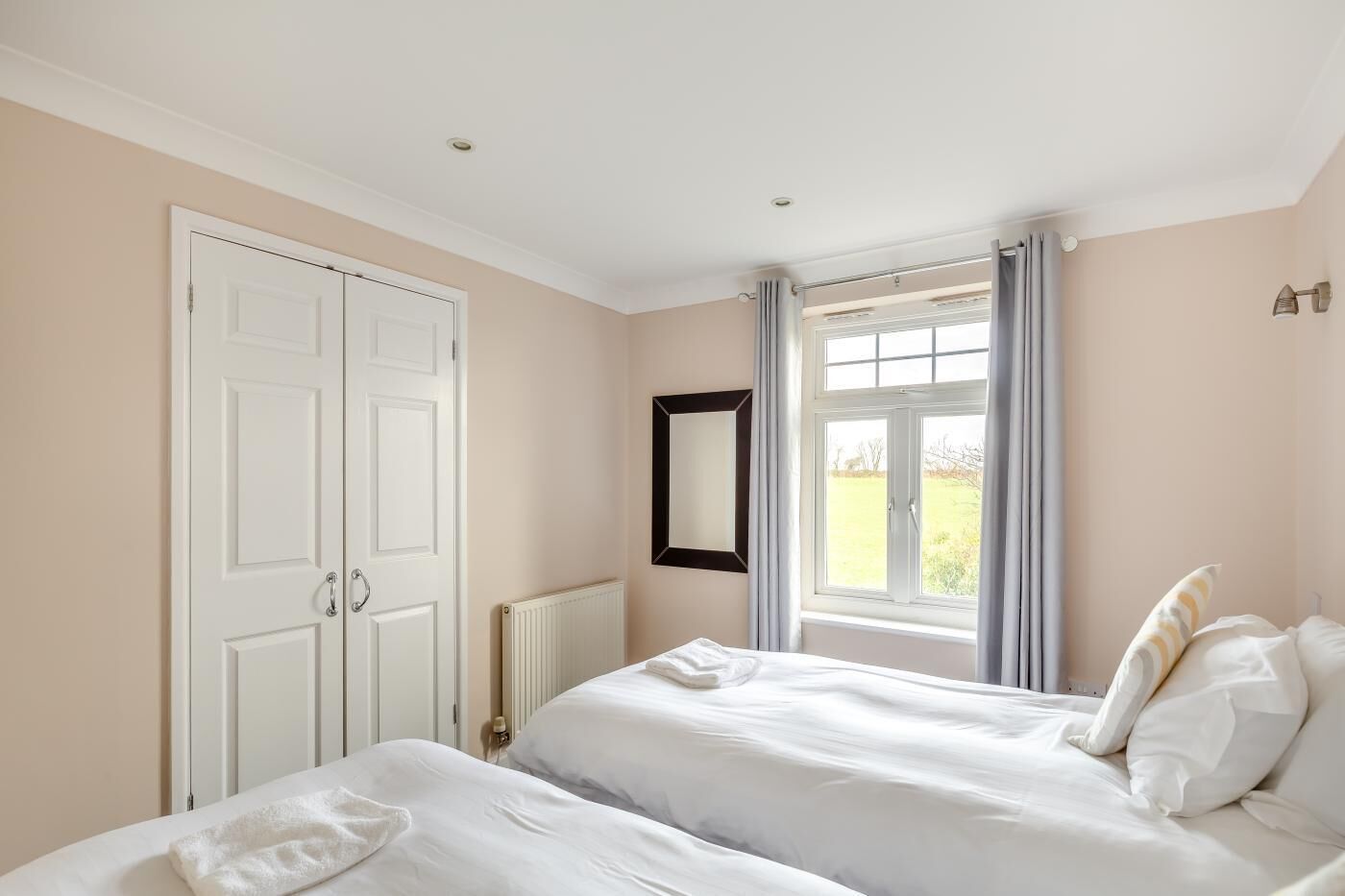 Un dormitorio con dos camas, una ventana con cortinas, un radiador y una puerta.