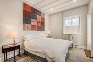A bedroom with a large bed, two bedside tables, a radiator, and a window. - 2 Bed in Sizewell (oc-w34607) (Sizewell)