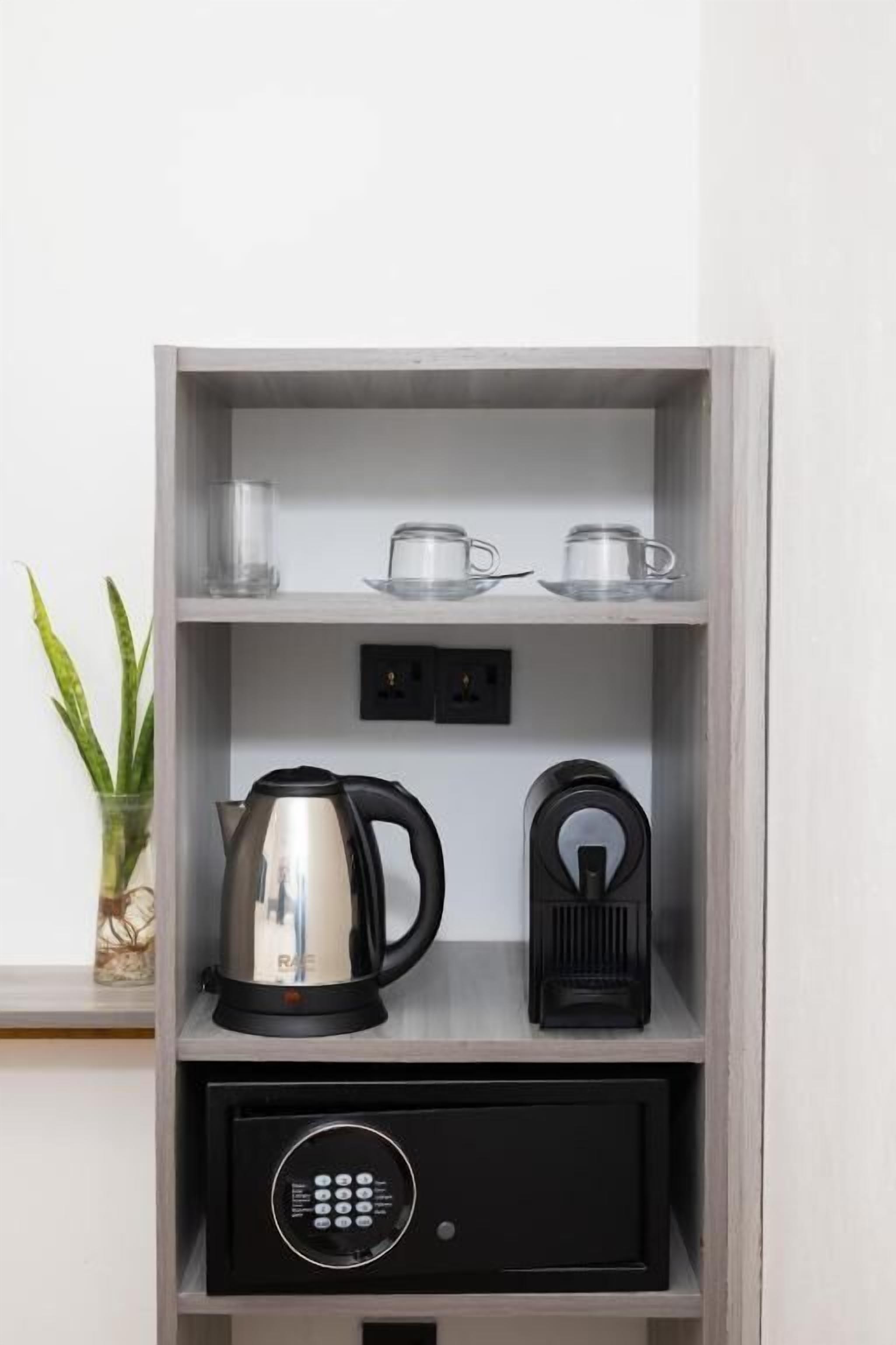 A shelf with a kettle, a coffee maker, and a small electronic device.