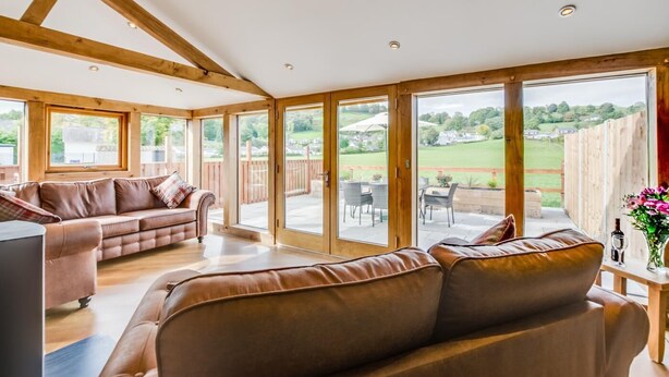 A spacious living area with a sofa, a television, and a view of the outdoors through large windows. - 3 Bed in Bala (oc-bow69) (Bala)