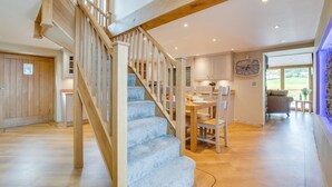 A staircase with wooden railings and blue carpeted steps leading to a dining area with a table and chairs. - 3 Bed in Bala (oc-bow69) (Bala)
