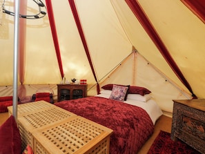 Una tenda con un letto, un tavolo e un baule decorativo.