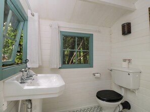 Un bagno con un lavandino bianco, una finestra con cornice verde, un water e un cartello con la scritta 'NON SCARICARE'.