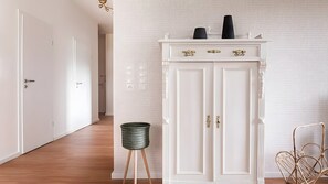 A hallway with a white wardrobe, a wicker basket, and a metal chair. - Apartment 'Flora' with Wi-Fi (Bad Zwischenahn)