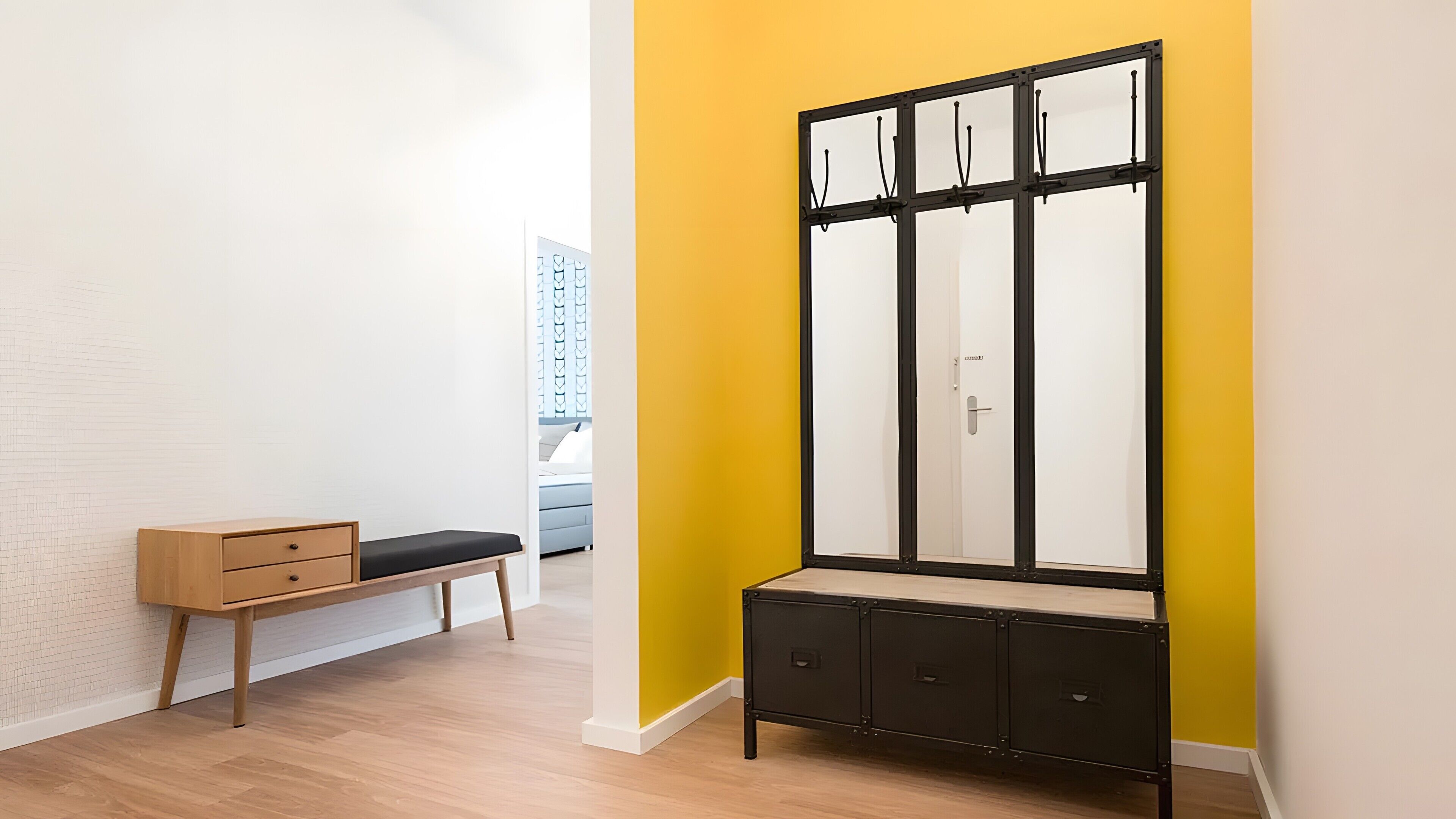 Un couloir avec un banc, une armoire et une porte donnant sur une autre pièce.