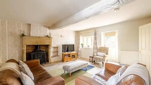 A living room with a fireplace, leather sofas, a television, and a plaid armchair. - 3 Bed in Stoney Middleton (oc-c34611) (Stoney Middleton)