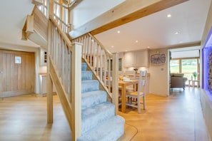 A staircase with wooden railings and blue carpeted steps leading to a dining area with a table and chairs. - 4 Bed in Bala (oc-bow66) (Bala)