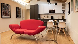 A modern kitchen with white cabinets, a red chair, and a dining table with chairs. - Apartment 'Flat 1' with Wi-Fi and Air Conditioning (Portese)