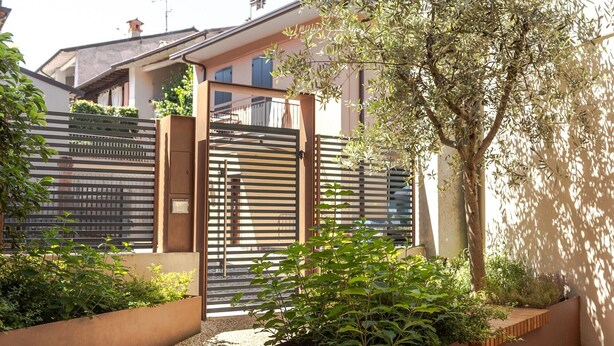A modern outdoor area with a gated entrance, a tree, and a building in the background. - Apartment 'Flat 1' with Wi-Fi and Air Conditioning (Portese)