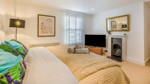 Quarto com cama, televisão, lareira e janela com persianas.