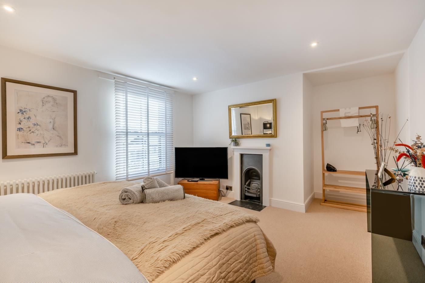 Een slaapkamer met een bed, een televisie, een open haard en een spiegel.