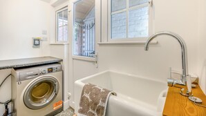 Casa de banho compacta com máquina de lavar, banheira e janela com vista.