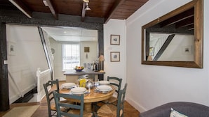 A dining area with a round table set for four, surrounded by chairs with woven seats. - 2 Bed in St Ives (oc-pvw38) (Saint Ives)