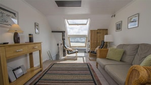 A cozy living room with a sofa, chairs, a wooden desk, and a large window. - 2 Bed in St Ives (oc-pvw38) (Saint Ives)