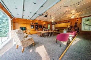 Ein geräumiges Wohnzimmer mit großem Fernseher, Holzmöbeln und einem Essbereich.