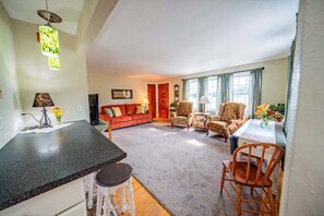 A spacious living area with a sofa, chairs, a dining table, and a kitchen area with a countertop and stools. - Superb 2-bedroom house in Cannon Falls perfect for relaxing getaway (Cannon Falls)