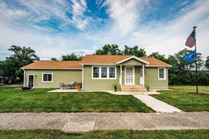 A single-story house with a front porch, a small front yard, and a flagpole with flags. - Superb 2-bedroom house in Cannon Falls perfect for relaxing getaway (Cannon Falls)