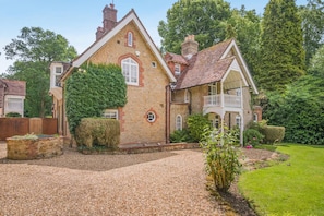 A two-story house with a stone facade, a tiled roof, and a front porch. - 6 Bed in Haslemere (oc-c34083) (Haslemere)