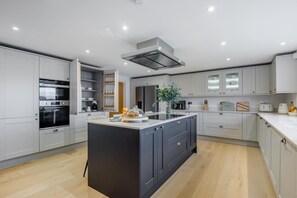 A modern kitchen with built-in appliances, a central island, and a large window. - 4 Bed in Penshore (oc-t34672) (Pensham)