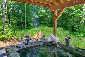 A hot tub with chairs and a fire pit in a forested area. - Bellaria Tremblant - Private villa with SPA (Mont-Tremblant)