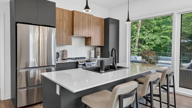 Een moderne keuken met een groot eiland, roestvrijstalen apparatuur en uitzicht op de omgeving.