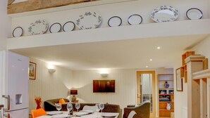 Un coin repas avec un plafond en bois, un réfrigérateur blanc et une table dressée pour quatre personnes.