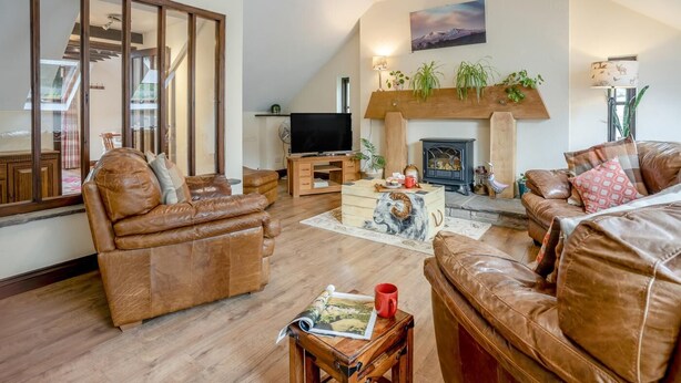 A living room with leather sofas, a television, a fireplace, and a large window. - 2 Bed in Trallong (oc-bow106) (Trallong)