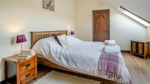 A bedroom with a wooden bed, a nightstand, a lamp, a door, and a small cabinet. - 2 Bed in Trallong (oc-bow106) (Trallong)