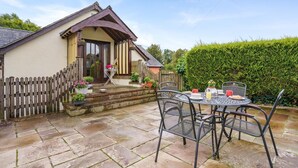 A house with a patio area featuring a round metal table and chairs, a wooden fence, and potted plants. - 2 Bed in Trallong (oc-bow106) (Trallong)