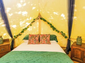 A bed with a canopy, green pillows, and a green bedspread. - Jungle Bell Tent (Newbury)