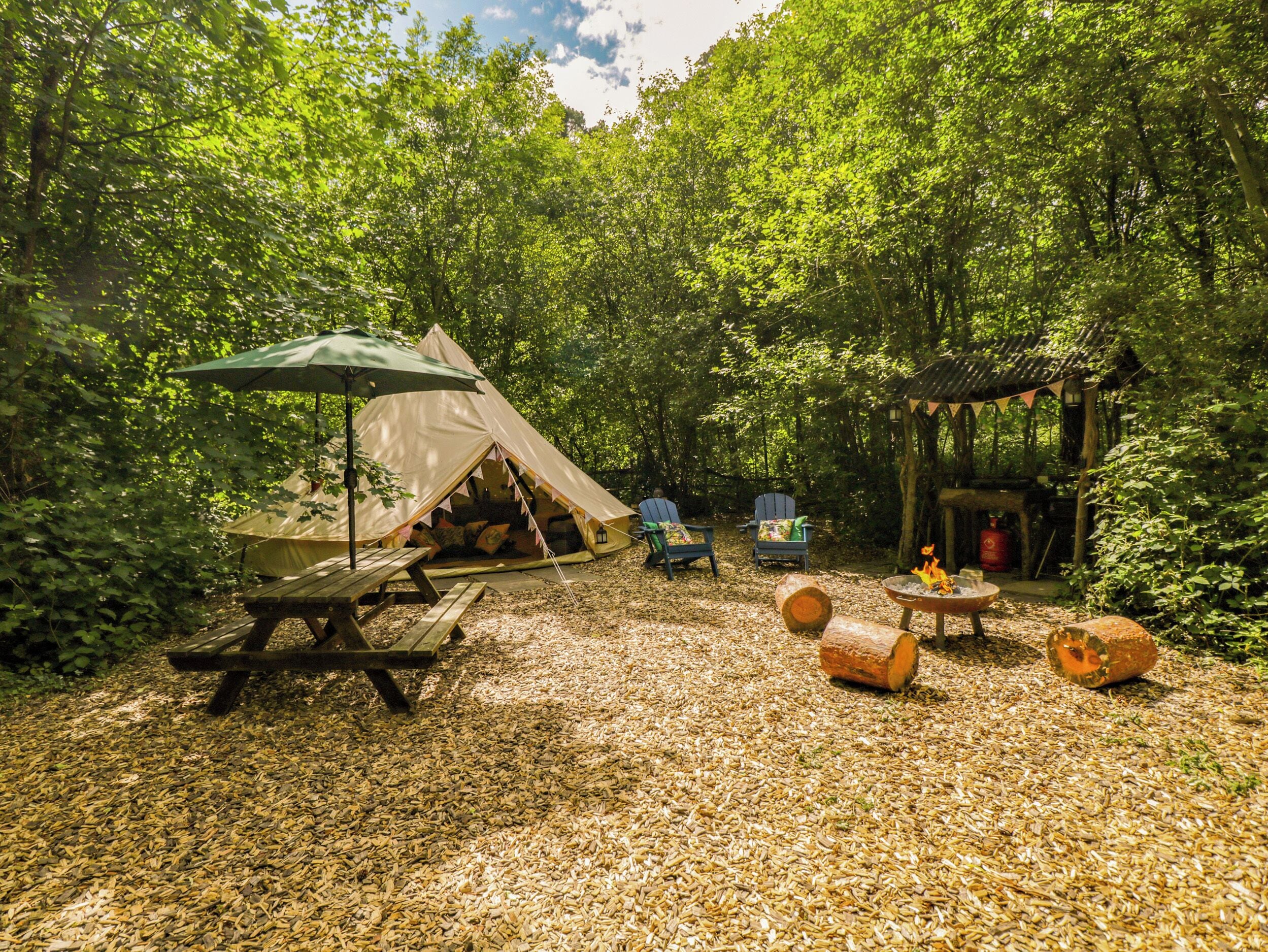Ein Campingplatz mit Zelten, Picknicktischen, Stühlen und einer Feuerstelle.
