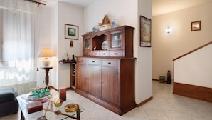 A living room with a wooden cabinet, a glass coffee table, and a lamp. - Girasole Apartment – Comfort & Fast WiFi in the Heart of Valdarno (Pestello)