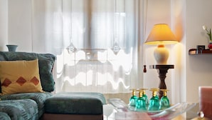 A living room with a sofa, a table with decorative bottles, and a lamp. - Girasole Apartment – Comfort & Fast WiFi in the Heart of Valdarno (Pestello)