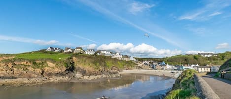A coastal town with houses on a hillside, a beach, and a clear sky.