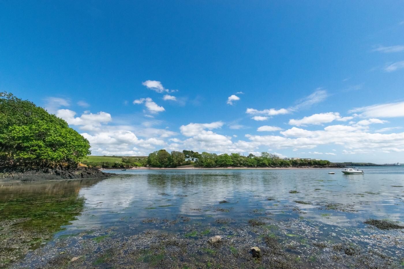 Un paysage côtier avec un ciel dégagé, une eau calme et un bateau.