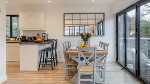 Una cucina moderna con isola centrale, zona pranzo con sedie, un'ampia finestra e vista all'esterno.