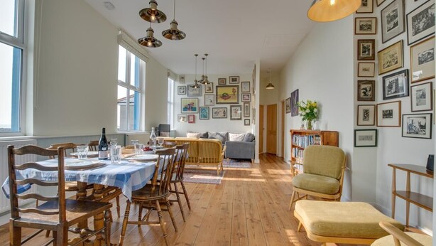 A dining area with a wooden table and chairs, a sofa, and a bookshelf. - 3 Bed in Aberystwyth (oc-bow115) (Aberystwyth)