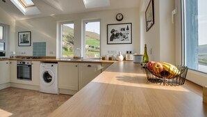 A modern kitchen with skylights, a washing machine, and a fruit bowl. - 3 Bed in Aberystwyth (oc-bow115) (Aberystwyth)
