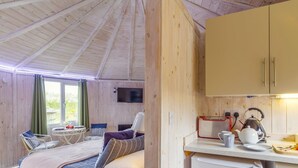 A cozy room with a bed, a small table, a chair, and a kitchenette with a kettle and a toaster. - 1 Bed in Hartland (oc-h34690) (Hartland)