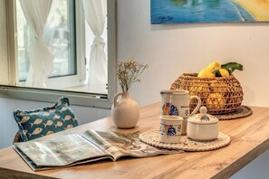 Ein Holztisch mit einer Zeitung, einer Vase mit Trockenblumen, einem Korb voller Zitronen und einer dekorativen Kanne.