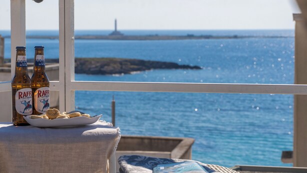 Blick auf das Meer mit Bierflaschen, einer Snackplatte und einer gemütlichen Sitzecke.