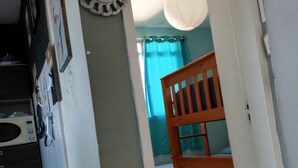 A narrow hallway with a wooden bench, a wall-mounted decorative plate, and a ceiling light fixture.
