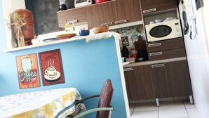 A kitchen with a blue wall, a coffee shop sign, a microwave, and a clock.